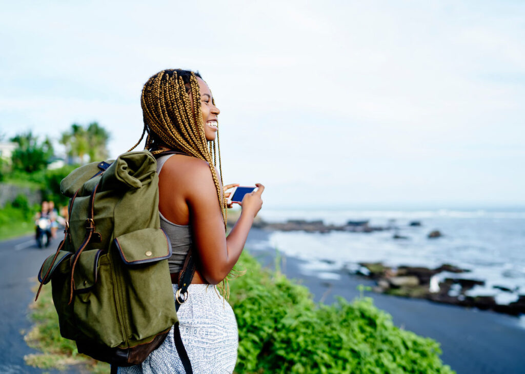 happy female traveler wearing a backpack 1200x854 1